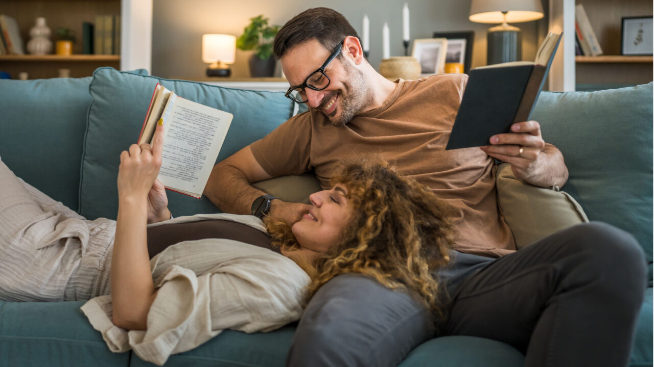 Happy couple reading on couch.