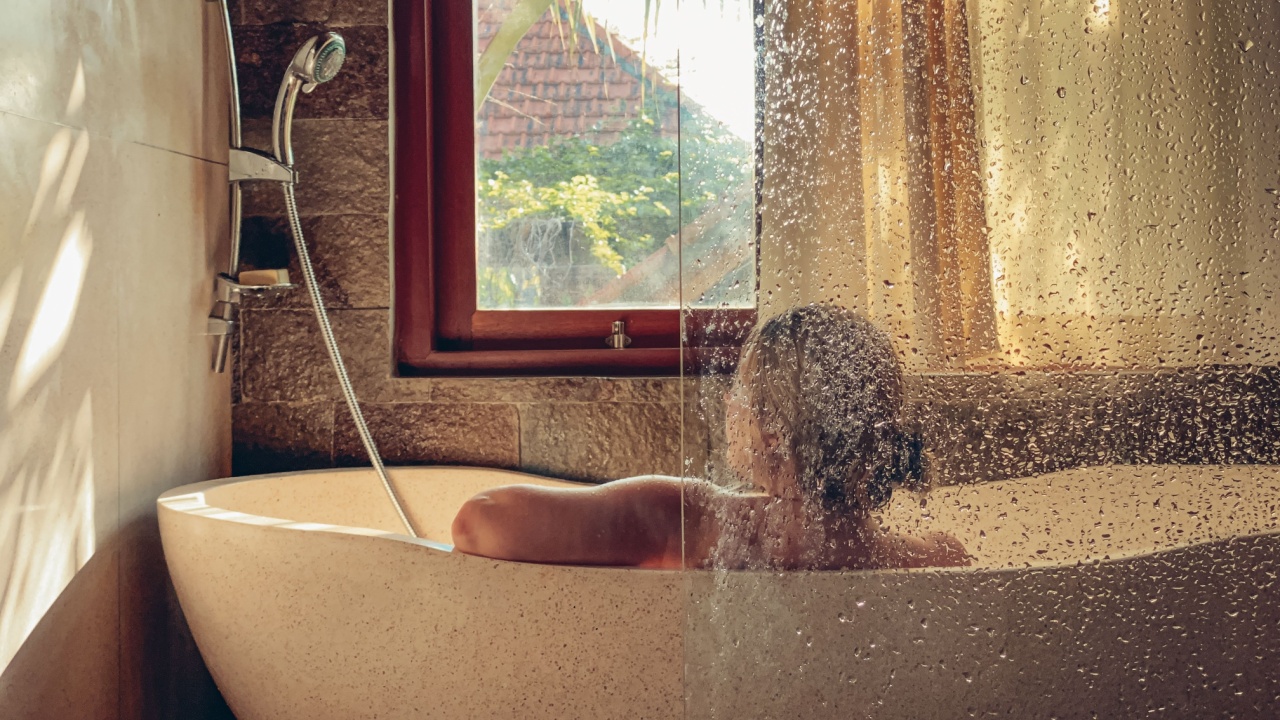 woman taking a relaxing bath in a bathroom with a window.