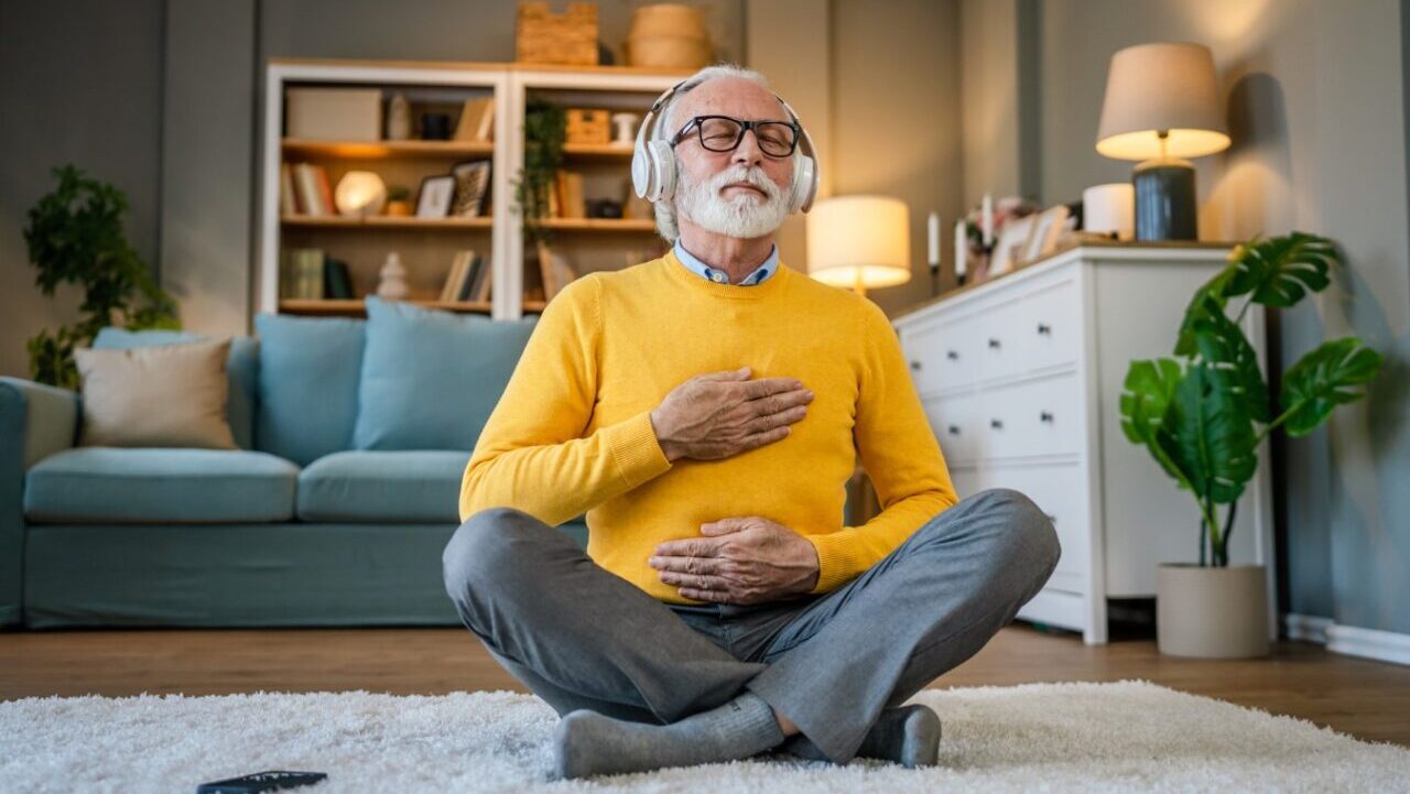 senior man practice guided meditation manifestation at home.