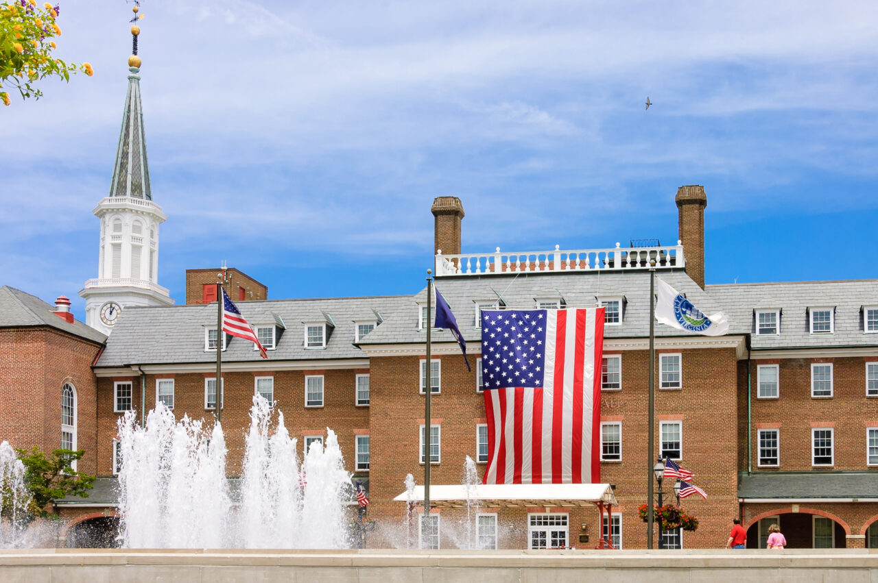 front of Alexandria city hall with fountains and a U.S. flag hanging on the front.