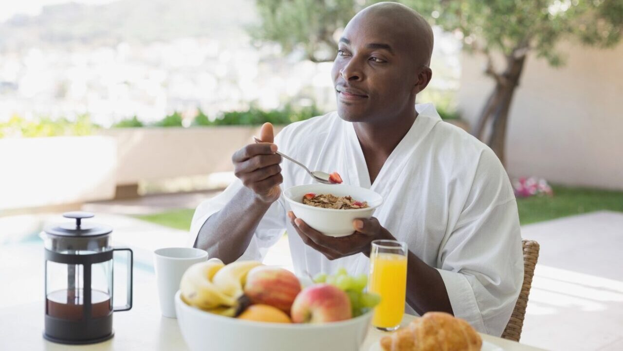 Handsome man in bathrobe having breakfast outside.