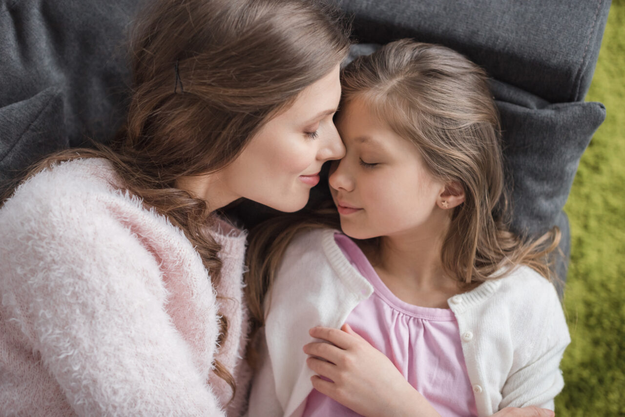 peaceful looking mom cuddling with daughter. Both look happy.