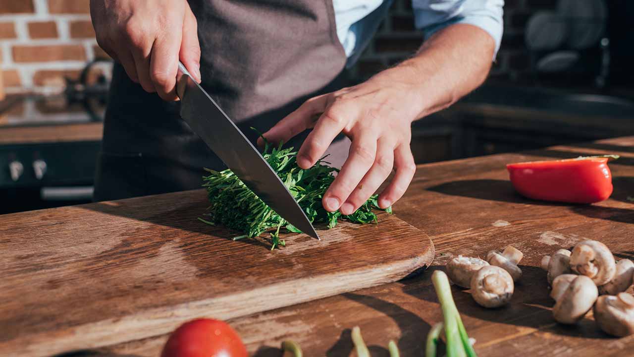 chopping board area in the kitchen with person prepping vegetables.