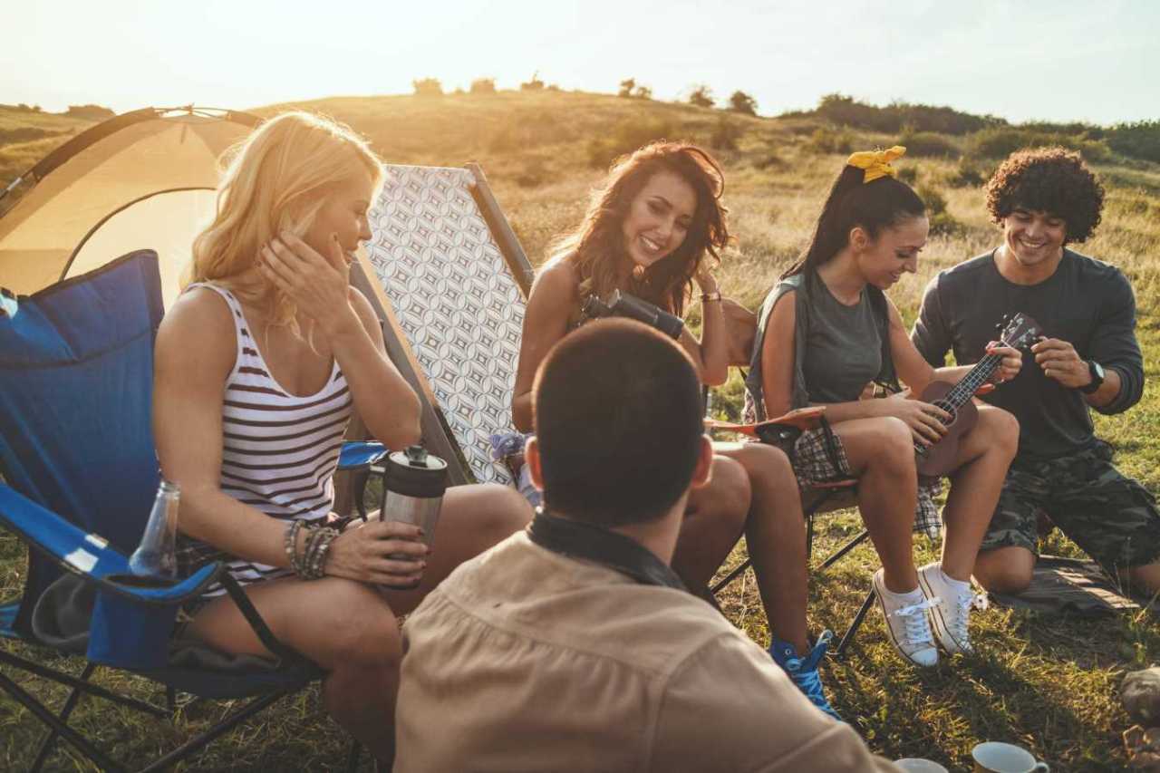 Happy Picnic with friends sitting together outside in camp chairs.