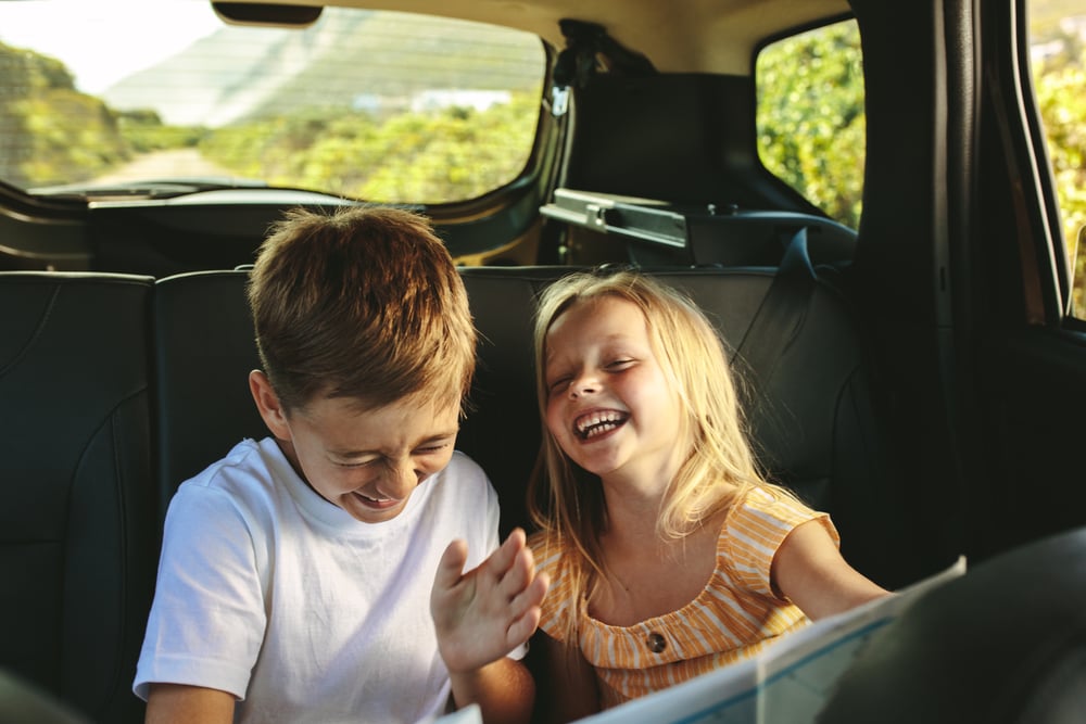 Two Kids in back of car laughing