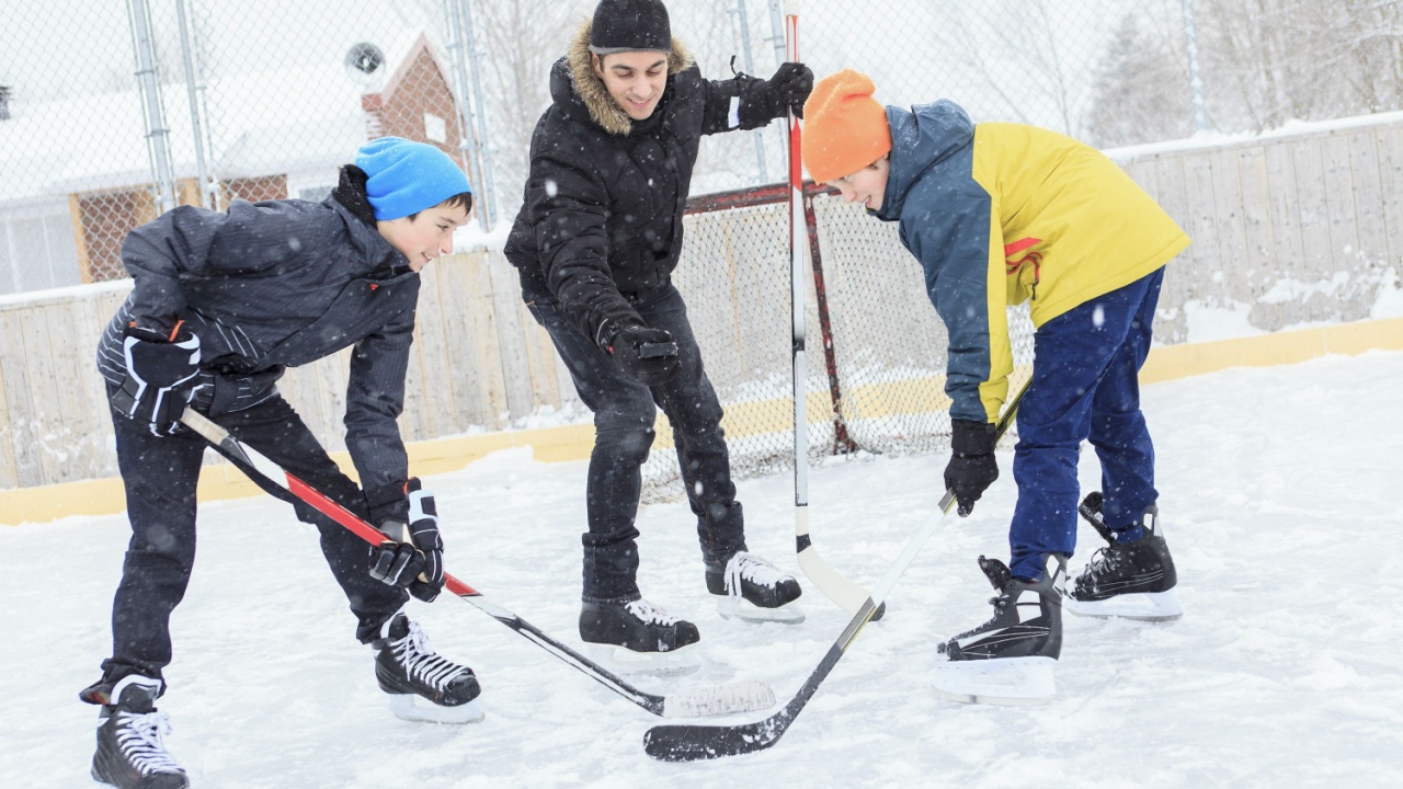 Teens play hockey together at outdoor ice rink.