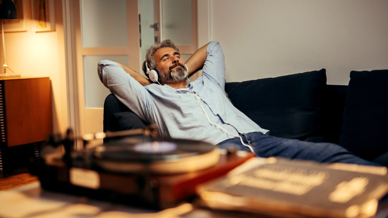 Man resting on couch listening to music looking peaceful.