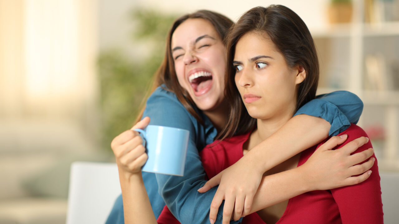 Excited woman hugs confused woman.